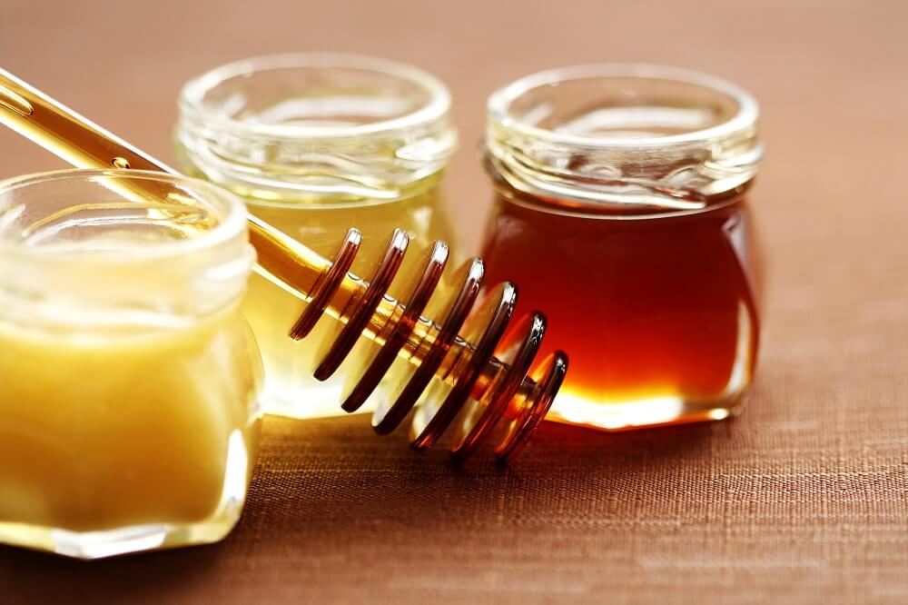 3 types of honey sitting on a table